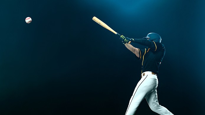 Baseball Player Hitting Ball Against Darkened Background
