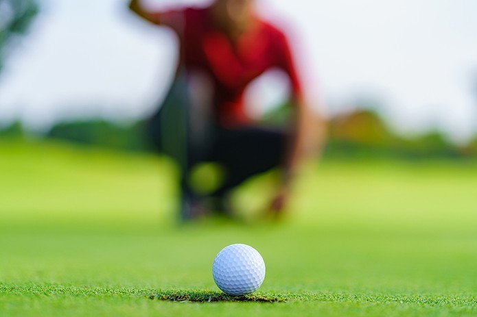 Blurred Golfer in Red Watching Putt
