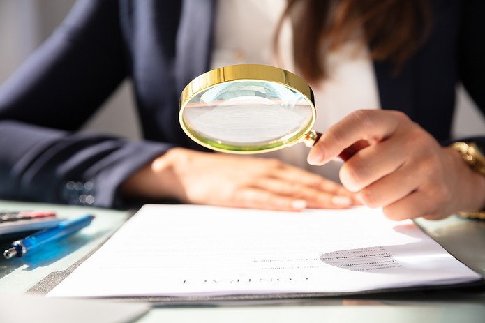 Businesswoman Holding Magnifying Glass Over Contract