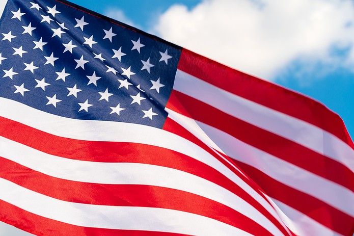 Close Up of USA Flag Against Blue Cloudy Sky