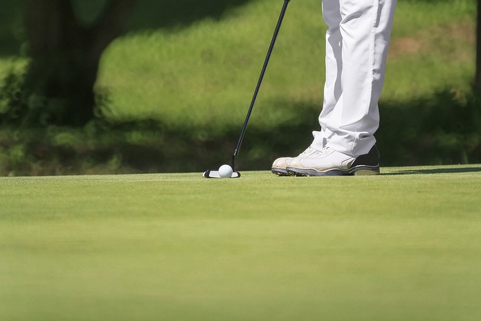 Feet of Golfer with Putter on Green