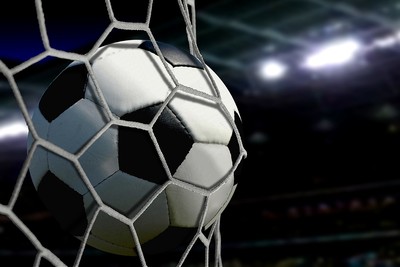 Football in Goal Net Against Stadium Light