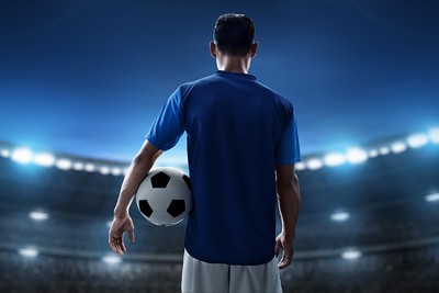 Footballer in Blue Shirt Holding Ball in Stadium