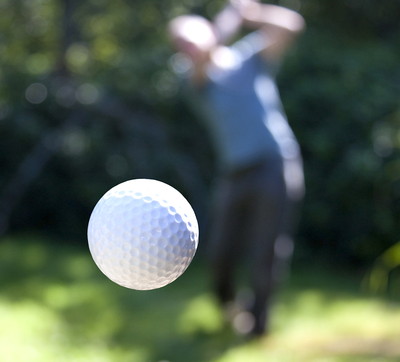 Golf Ball in Flight Against Blurred Player
