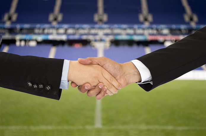 Handshake Against Blue Football Stadium