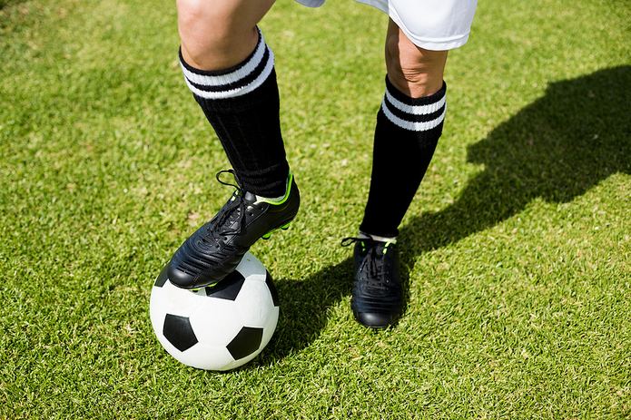 Legs of Female Footballer Standing on Ball
