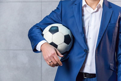 Man in Blue Suit with Football Under Arm
