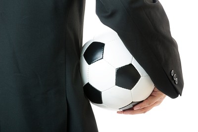 Man in Suit Holding Traditional Football Under Arm