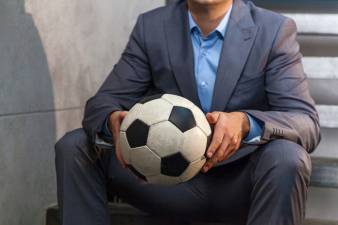 Man in Suit Sitting Holding Football