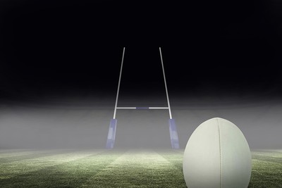 Rugby Ball and Posts in Darkened Stadium