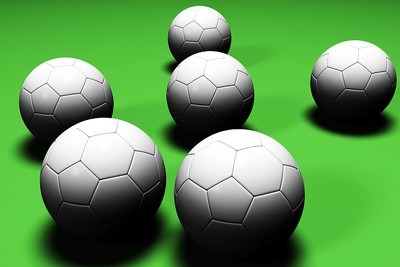 Six Footballs Against Green Background
