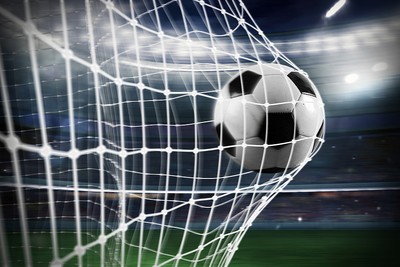Traditional Football Hitting Goal Net in Blurred Stadium