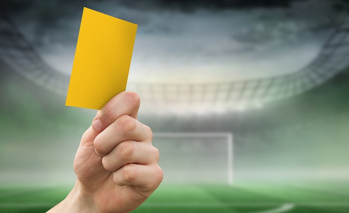 Yellow Card Shown Against Blurred Stadium