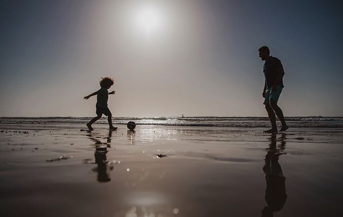 Father son playing football on holiday