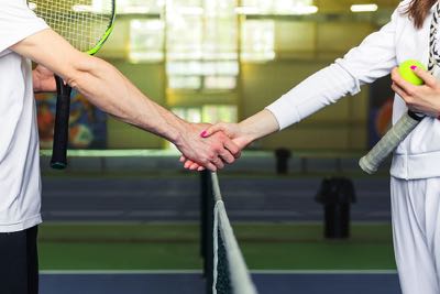 Pria dan wanita berjabat tangan sebelum bermain tenis