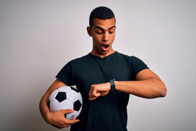 Man with football looking at watch